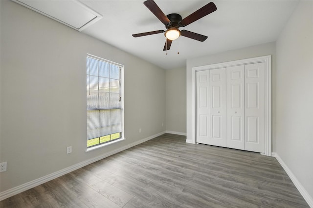 unfurnished bedroom with baseboards, wood finished floors, multiple windows, and a closet