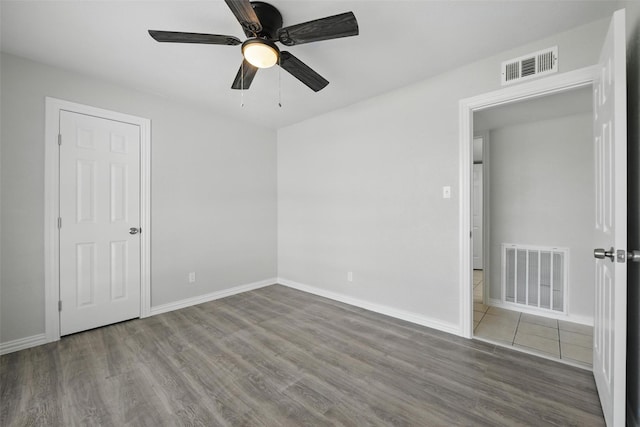 unfurnished bedroom featuring baseboards, wood finished floors, and visible vents