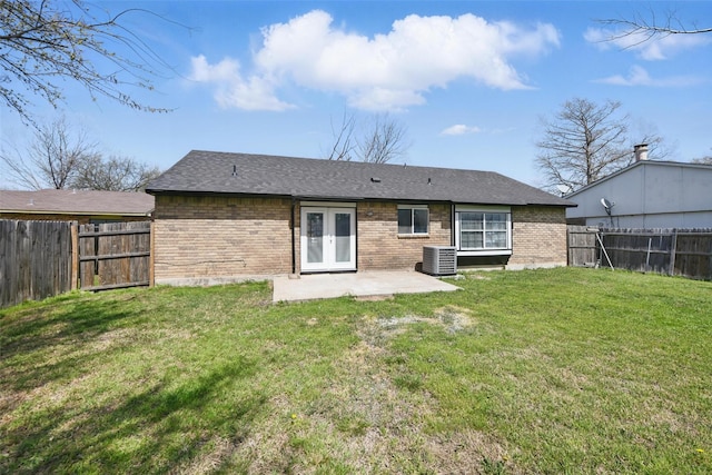rear view of house with central AC unit, french doors, brick siding, and a patio