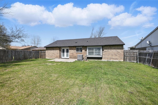 rear view of property with a fenced backyard, a yard, central air condition unit, a patio area, and brick siding