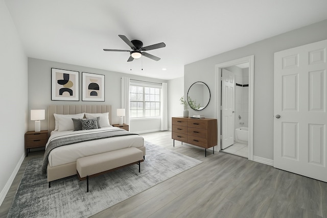 bedroom featuring ensuite bath, ceiling fan, baseboards, and wood finished floors