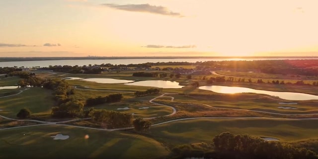 drone / aerial view featuring golf course view and a water view