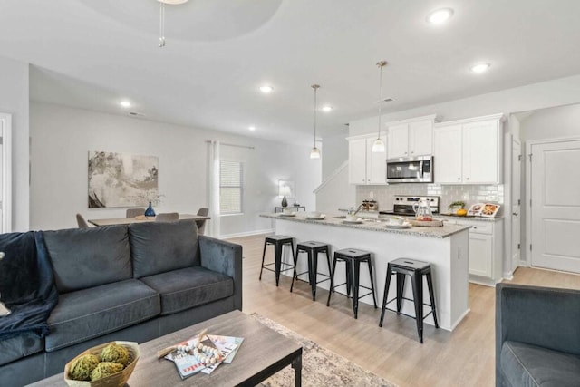 living room with recessed lighting, baseboards, and light wood-type flooring