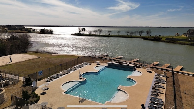 pool with a patio, a water view, and fence