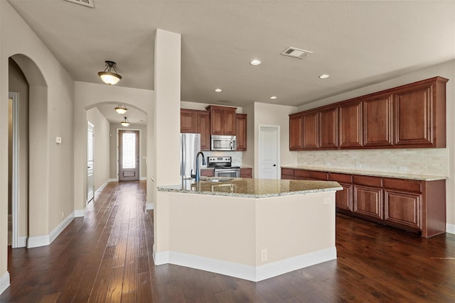 1305 Greenrock Ct, Midlothian, TX 76065 - kitchen featuring appliances with stainless steel finishes, arched walkways, tasteful backsplash, dark wood-style flooring, and recessed lighting