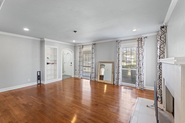 2508 Carnation Ave, Fort Worth, TX 76111 - unfurnished living room featuring arched walkways, ornamental molding, wood finished floors, baseboards, and built in features