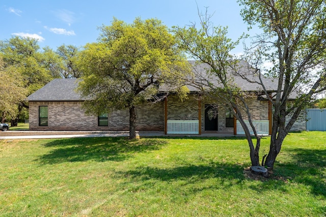 ranch-style house featuring brick siding, a front yard, and roof with shingles