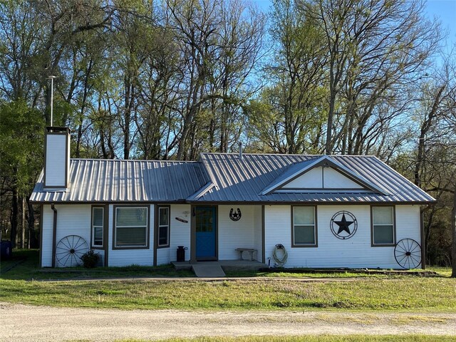 view of front of property featuring a front lawn, metal roof, and a chimney