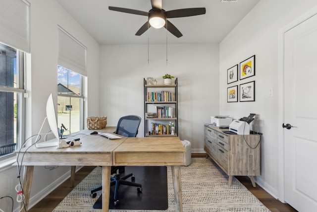 home office with baseboards, visible vents, ceiling fan, and wood finished floors