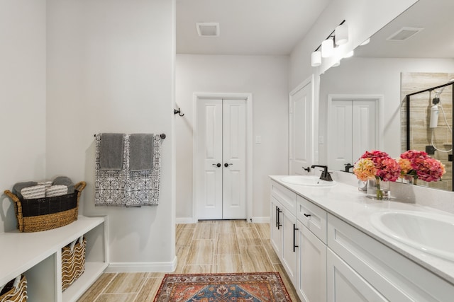 full bath featuring double vanity, a sink, visible vents, and a shower stall