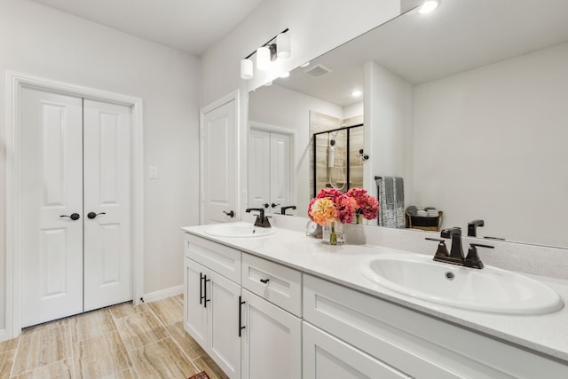bathroom featuring visible vents, a sink, a stall shower, and double vanity