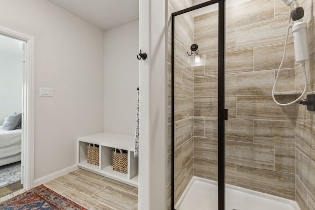 bathroom with a stall shower, ensuite bathroom, and baseboards