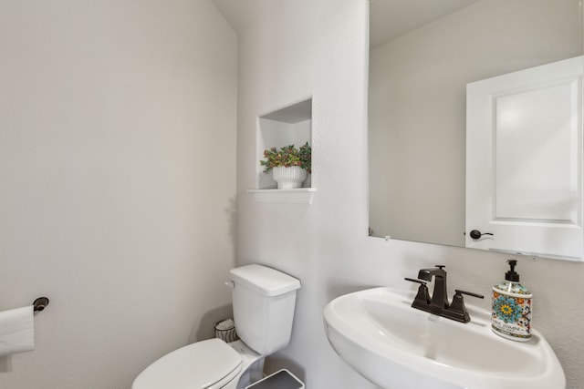half bathroom featuring toilet and a sink