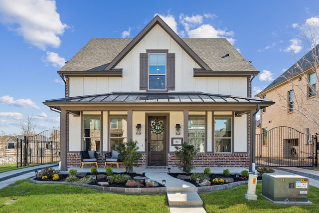 modern farmhouse style home featuring brick siding, a gate, a standing seam roof, and metal roof