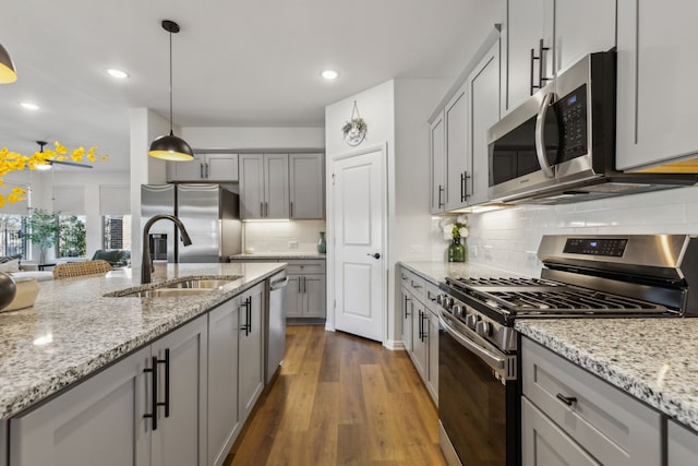 kitchen with a sink, stainless steel appliances, dark wood-style floors, and gray cabinetry