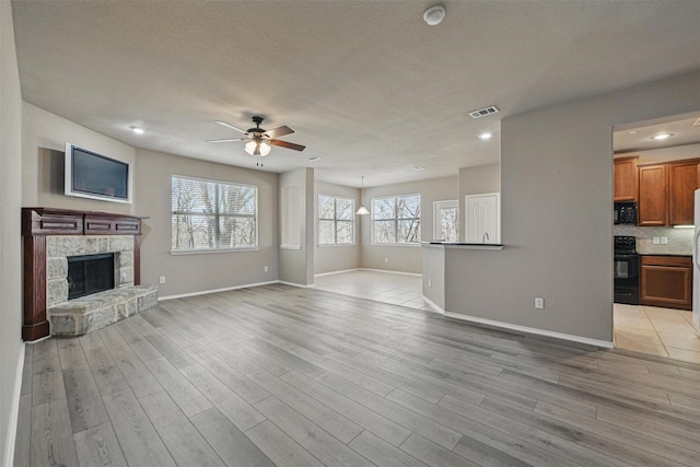 804 Starling Ln, Aubrey, TX 76227 - unfurnished living room with a ceiling fan, light wood-style floors, baseboards, recessed lighting, and a stone fireplace