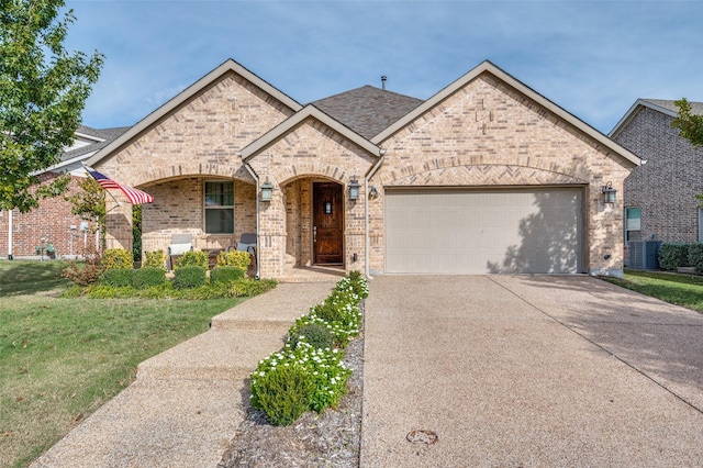 french country inspired facade with a front yard, driveway, a porch, an attached garage, and brick siding