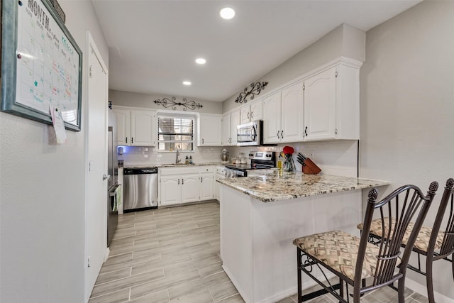 702 Middle Glen Dr, Garland, TX 75043 - kitchen featuring a sink, a peninsula, stainless steel appliances, and white cabinetry