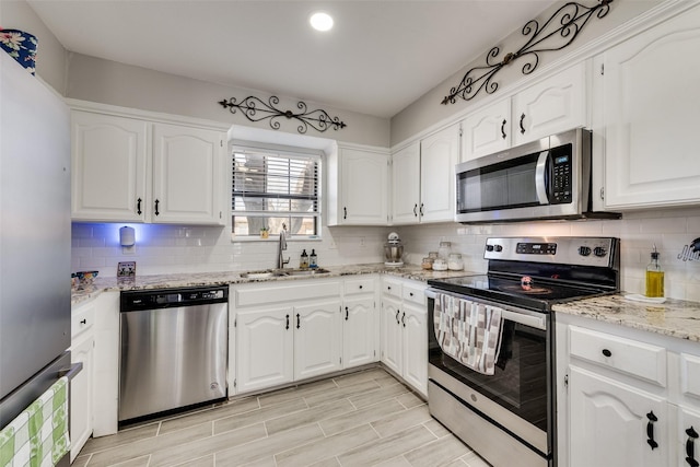 702 Middle Glen Dr, Garland, TX 75043 - kitchen featuring appliances with stainless steel finishes, white cabinetry, light stone counters, and a sink