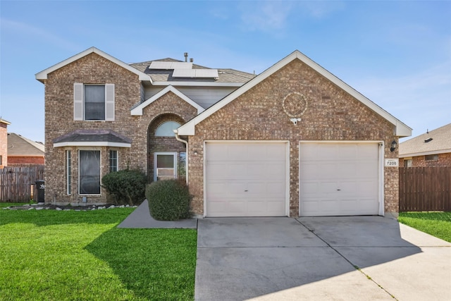 traditional-style home with a front lawn, fence, concrete driveway, brick siding, and solar panels