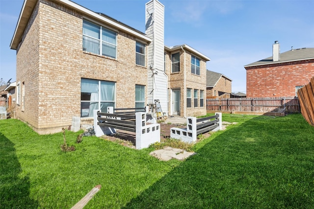 rear view of house featuring brick siding, a lawn, a chimney, and fence