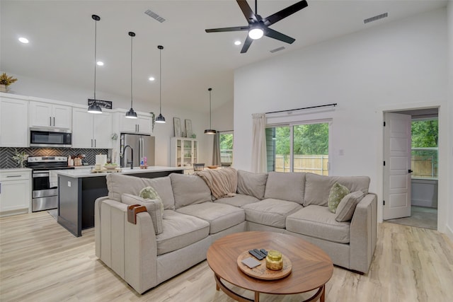 living area with visible vents, a towering ceiling, and ceiling fan