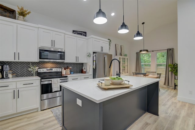 kitchen with light wood-type flooring, tasteful backsplash, white cabinetry, appliances with stainless steel finishes, and light countertops