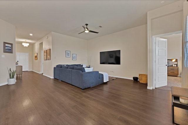 living room with dark wood finished floors, visible vents, ceiling fan with notable chandelier, and baseboards