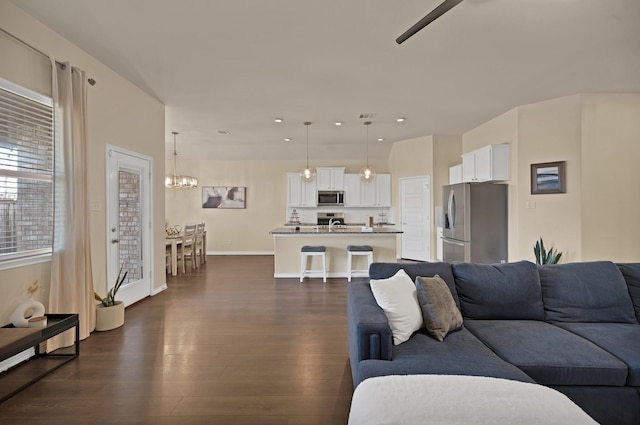 living room featuring dark wood-type flooring, recessed lighting, baseboards, and a chandelier
