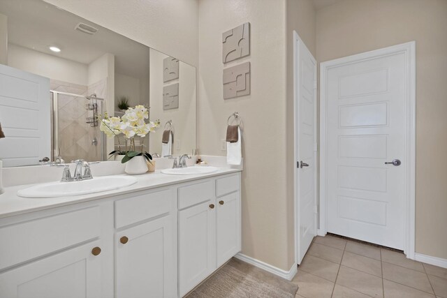 full bath with tile patterned floors, a stall shower, double vanity, and a sink