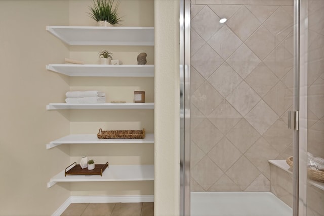 full bathroom featuring tile patterned flooring, a shower stall, and baseboards