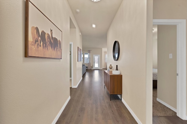 corridor with dark wood-type flooring and baseboards