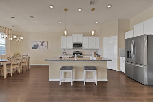 kitchen with visible vents, a sink, light stone counters, stainless steel appliances, and an inviting chandelier