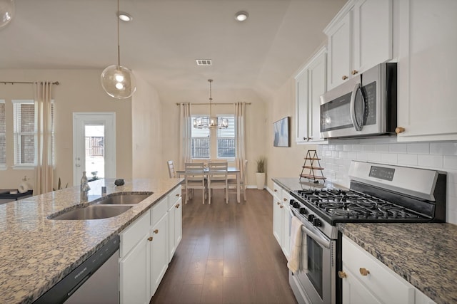 kitchen featuring dark wood-style floors, a sink, decorative backsplash, white cabinets, and appliances with stainless steel finishes