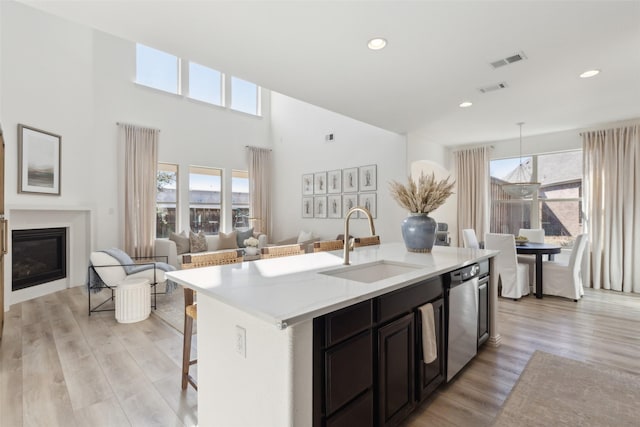 12000 Sunny St, Frisco, TX 75033 - kitchen with dishwasher, a center island with sink, light countertops, light wood-type flooring, and a kitchen bar