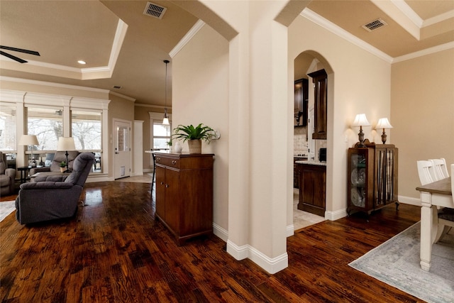 hallway with visible vents, arched walkways, crown molding, and wood finished floors