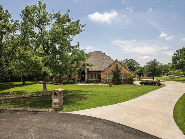 view of front of property featuring brick siding, a shingled roof, and a front lawn