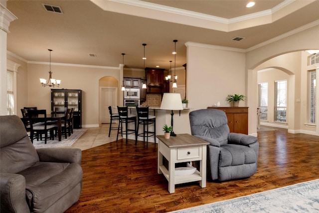 living area with arched walkways, visible vents, a healthy amount of sunlight, and an inviting chandelier