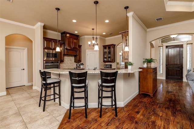 kitchen featuring visible vents, arched walkways, backsplash, and stainless steel appliances