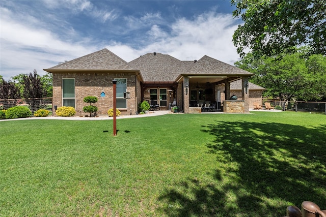 back of property with a patio area, brick siding, fence, a yard, and a shingled roof