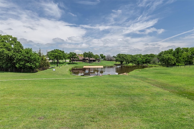 view of community featuring a water view, fence, and a yard