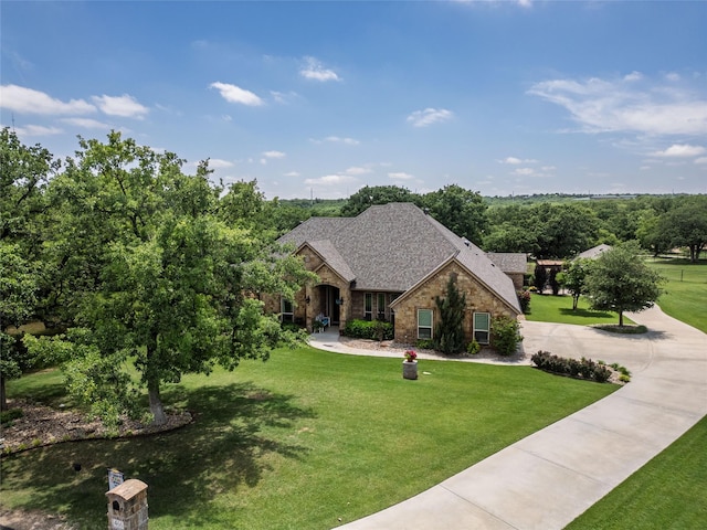 view of front of home featuring curved driveway, a front lawn, stone siding, and brick siding