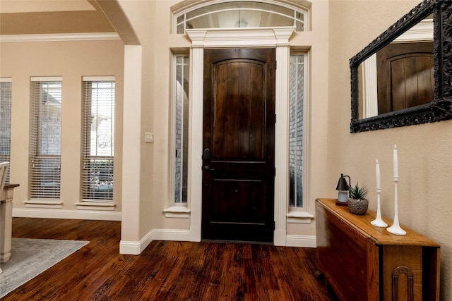 entryway with crown molding, baseboards, arched walkways, and wood finished floors