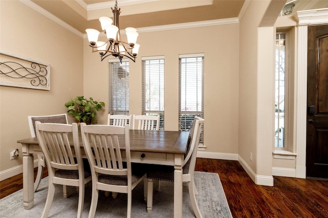 dining room with baseboards, ornamental molding, wood finished floors, and a notable chandelier