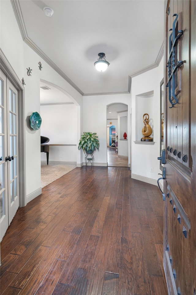 entrance foyer featuring crown molding, arched walkways, wood-type flooring, and baseboards