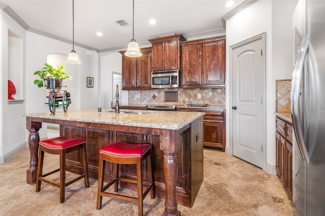kitchen featuring a sink, a kitchen island with sink, stainless steel appliances, decorative backsplash, and ornamental molding