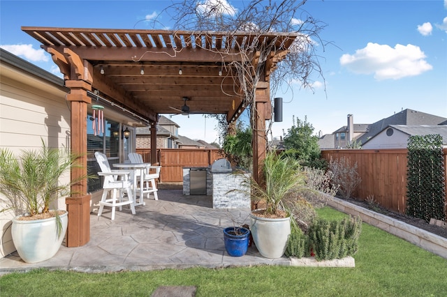 view of patio / terrace featuring a fenced backyard, ceiling fan, and an outdoor kitchen