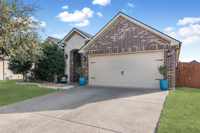 view of front of property featuring fence, brick siding, a garage, a front yard, and driveway