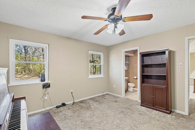 unfurnished bedroom with baseboards, carpet floors, ceiling fan, ensuite bathroom, and a textured ceiling