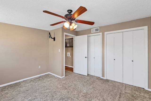 unfurnished bedroom featuring baseboards, visible vents, carpet floors, a textured ceiling, and two closets